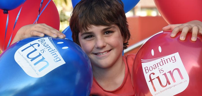 Close up of boy holing Expo balloons, with graphic "Boarding is Fun!"